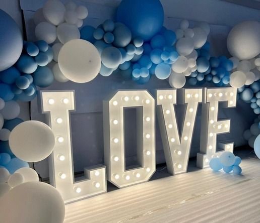 Lettres géantes lumineuses LOVE devant un mur de ballons