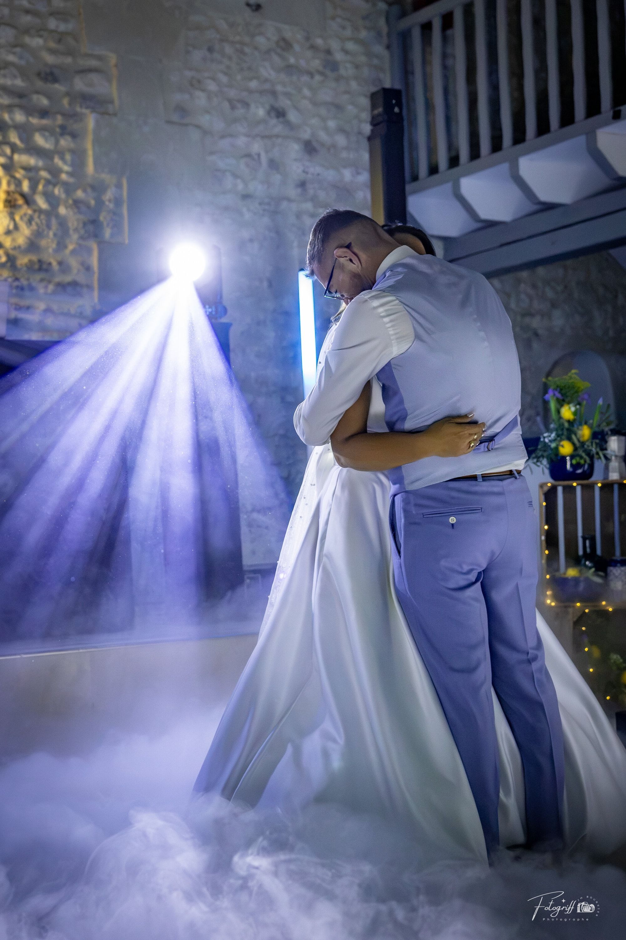 Les mariés enlacés pour leur première danse, dans la fumée lourde et un faisceau de lumière
