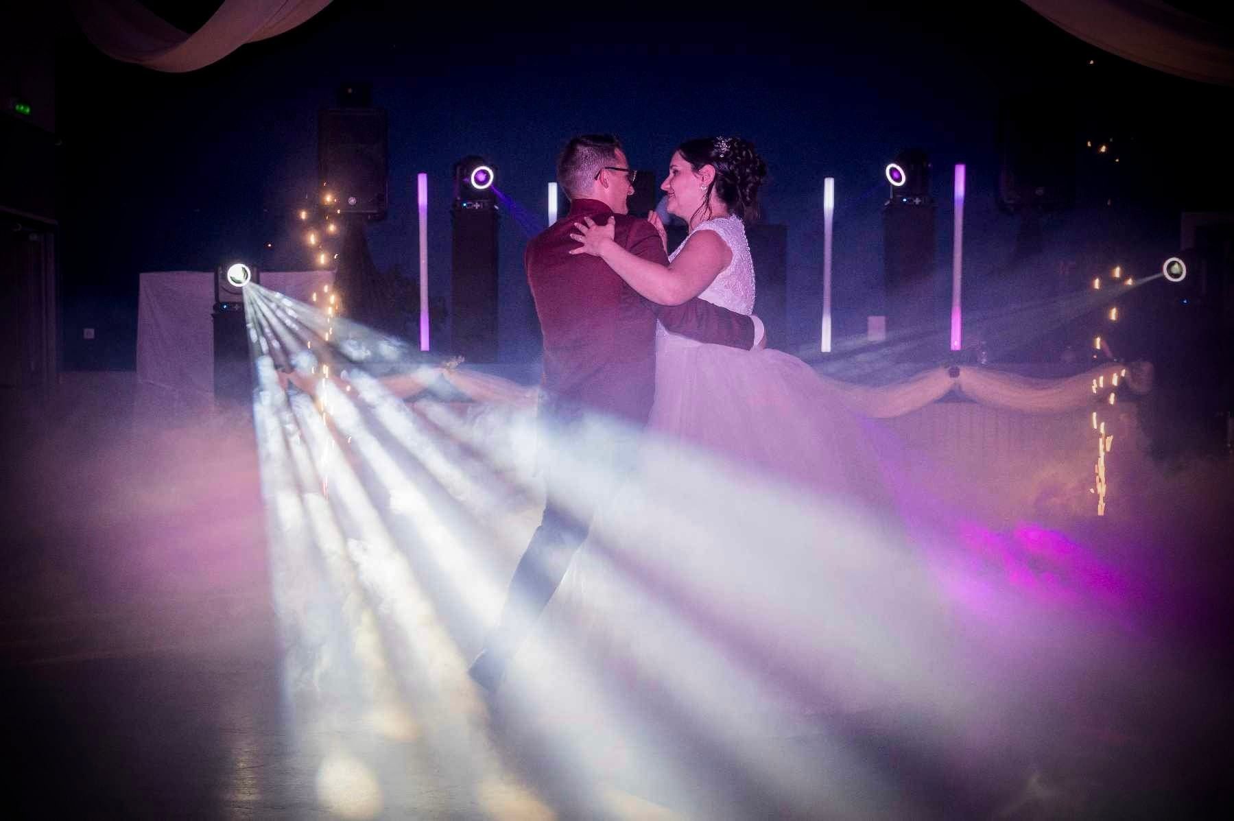 Première danse dans la fumée lourde, sous des faisceaux violets et des colonnes lumineuses