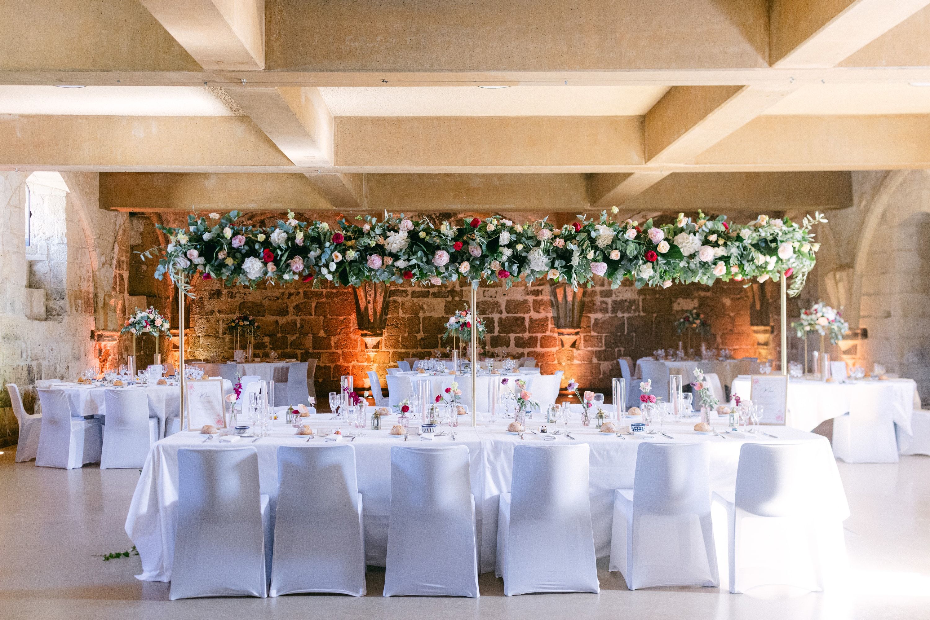 Table d’honneur sous une arche fleurie, dans une salle voûtée mise en lumière